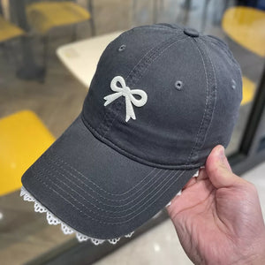 Grey baseball cap with embroidered white bow and lace trim