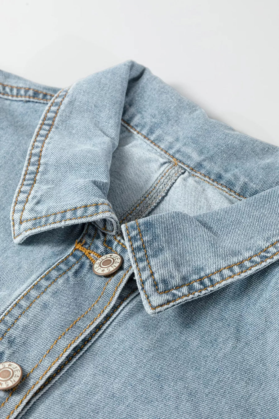 Light wash denim trucker jacket with button-down front and contrast stitching.