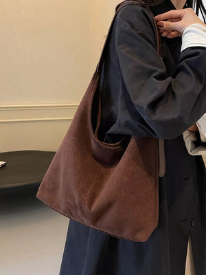 Brown suede hobo bag with adjustable strap and contrast stitching.