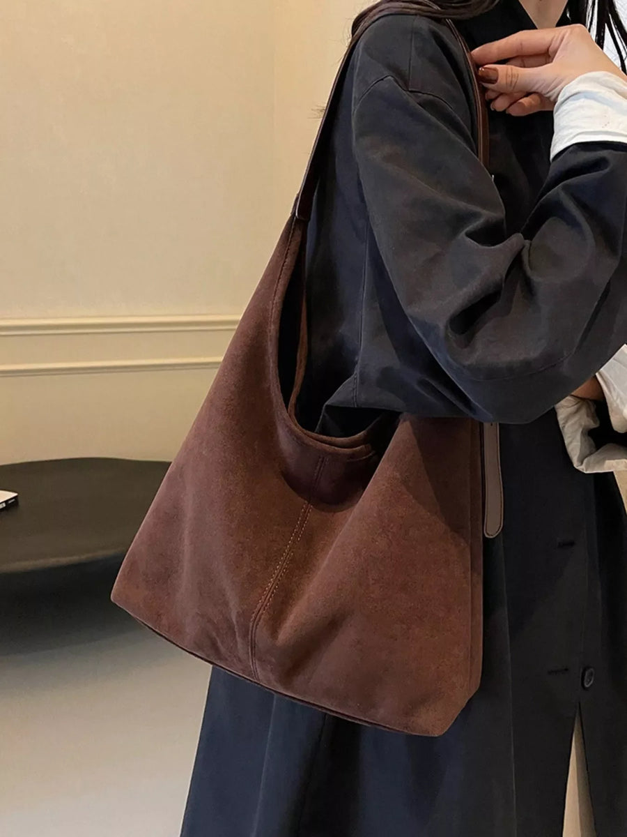 Brown suede hobo bag with adjustable strap and contrast stitching.