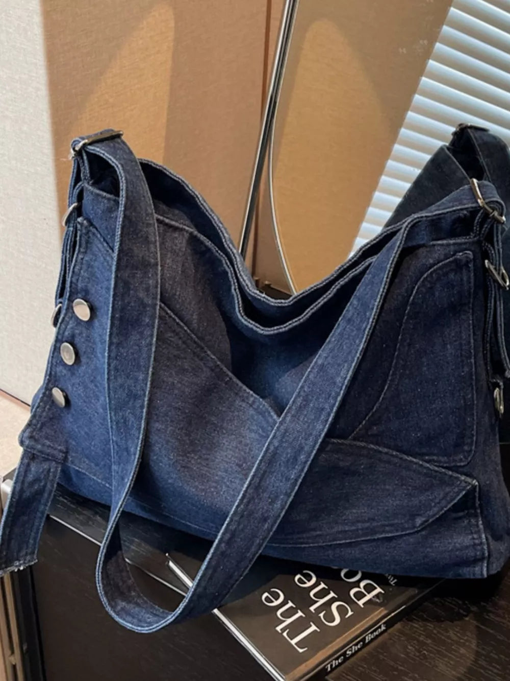 Relaxed denim crossbody bag with button accents and adjustable strap.