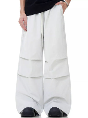 Men's wide-leg drawstring jogger pants in beige with layered pocket details.
