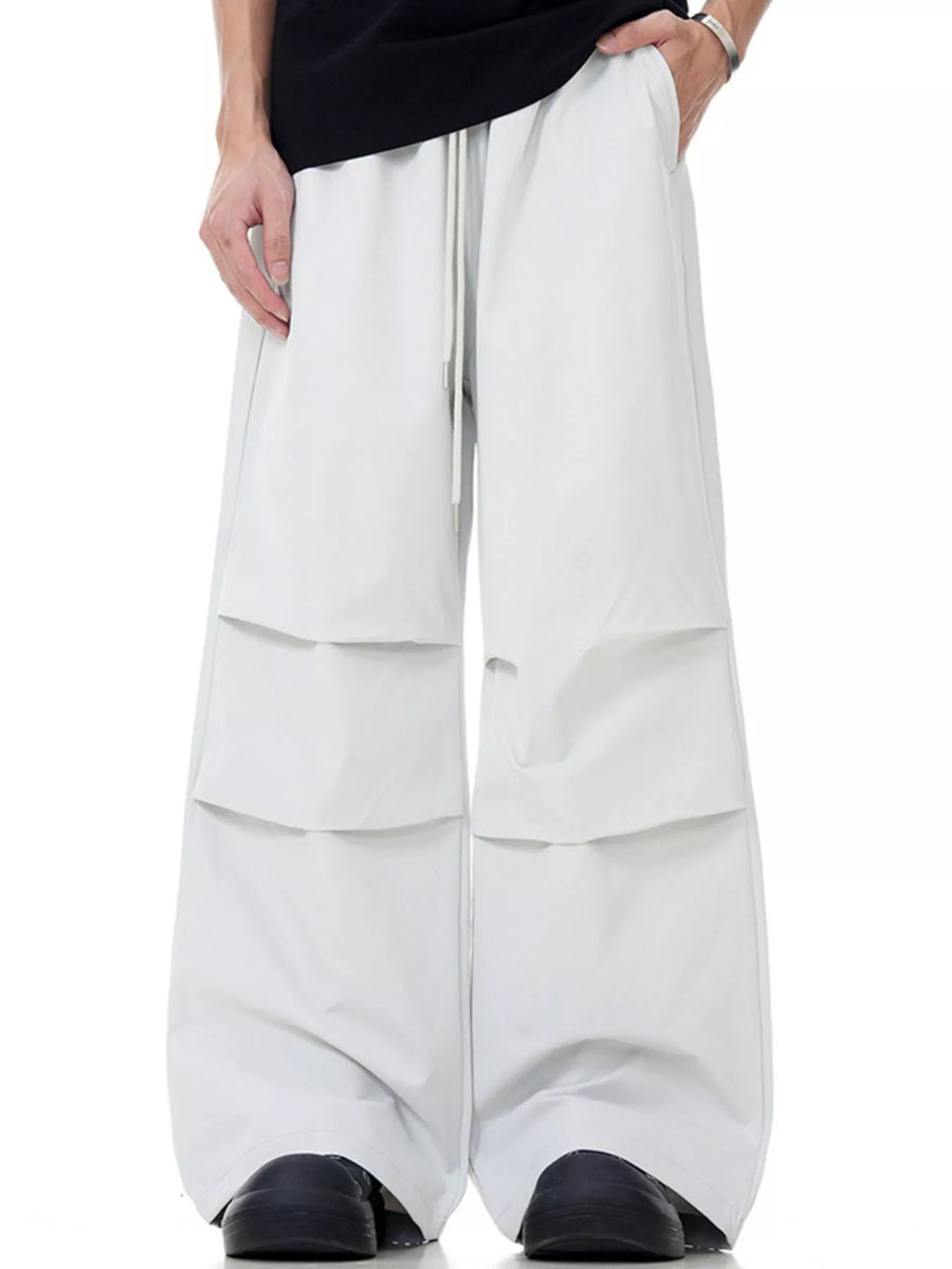 Men's wide-leg drawstring jogger pants in beige with layered pocket details.