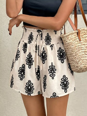 White shorts with black medallion print, smocked waist, and drawstring.