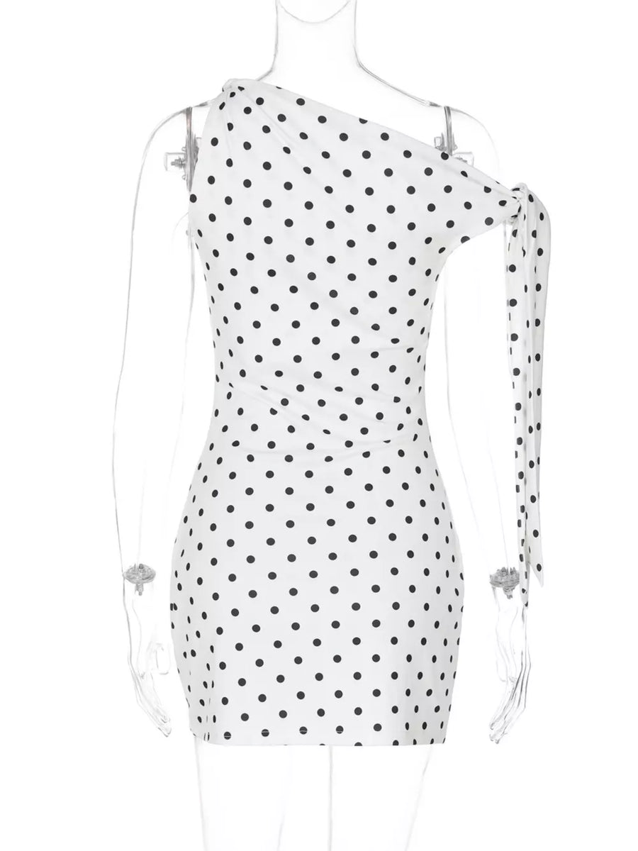 White polka dot mini dress with asymmetrical neckline and bow detail on sleeve.