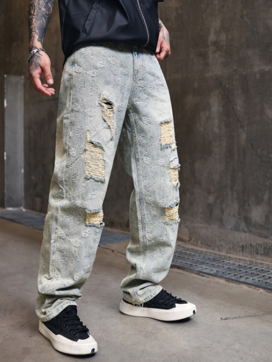 Distressed wide-leg men's jeans in light wash denim with paisley pattern and ripped details.