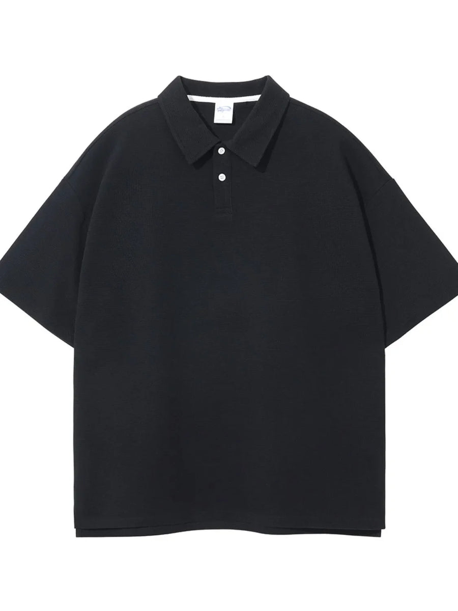 Black textured boxy polo shirt with short sleeves and a two-button placket.