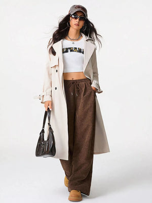 Brown corduroy drawstring pants with a relaxed fit and wide leg, styled with a crop top and trench coat.
