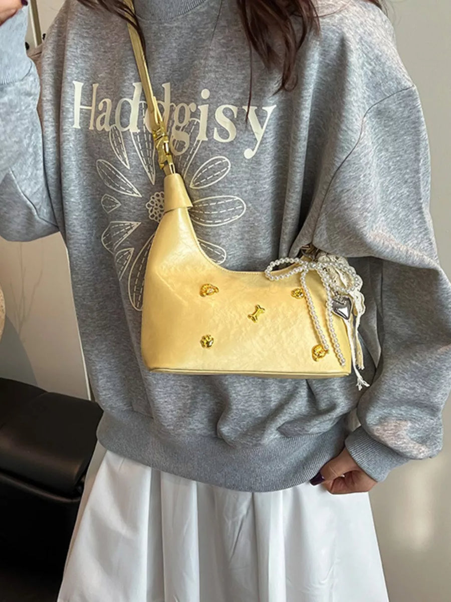 Pastel yellow hobo bag with gold accents and pearl charm detail
