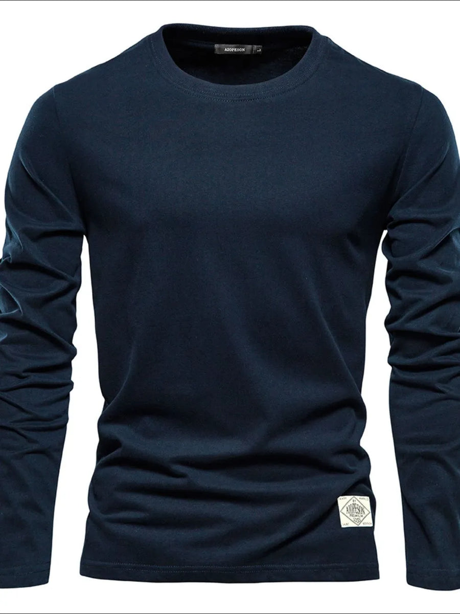 Navy crew-neck long-sleeve tee with a textured fabric and a diamond-shaped patch detail on the hem.