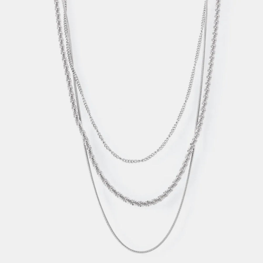 Delicate three-strand silver crystal necklace with layered chains and textured details.
