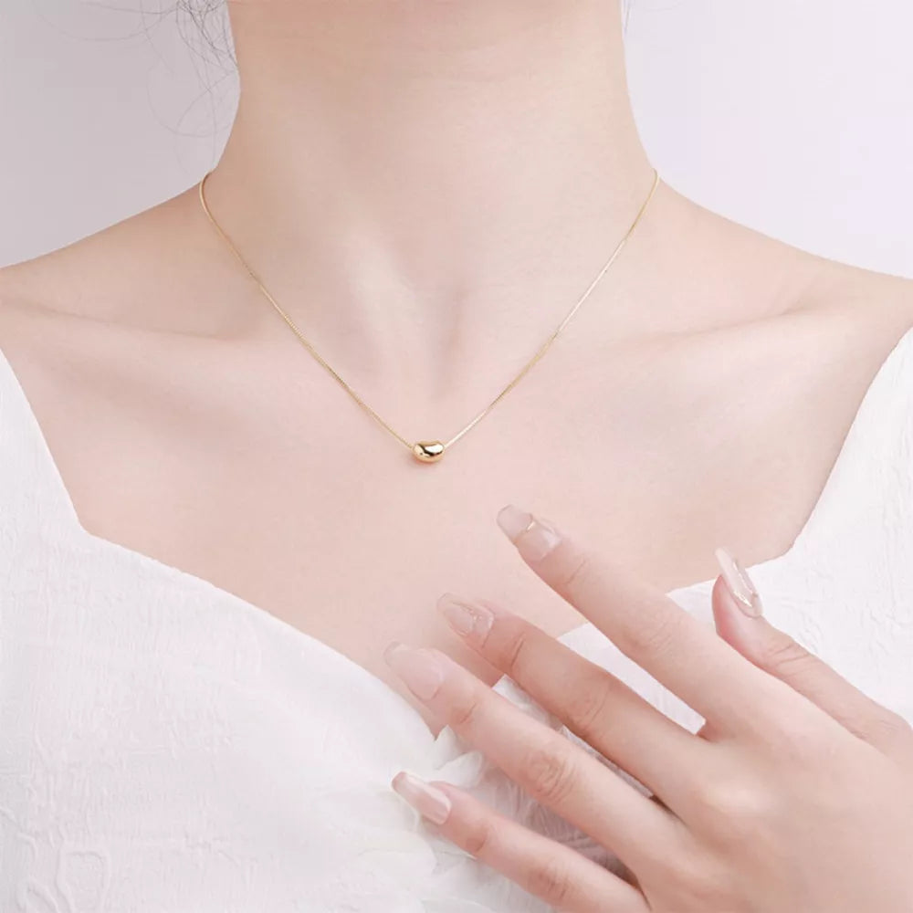 Gold bean pendant necklace on a delicate box chain, sterling silver.