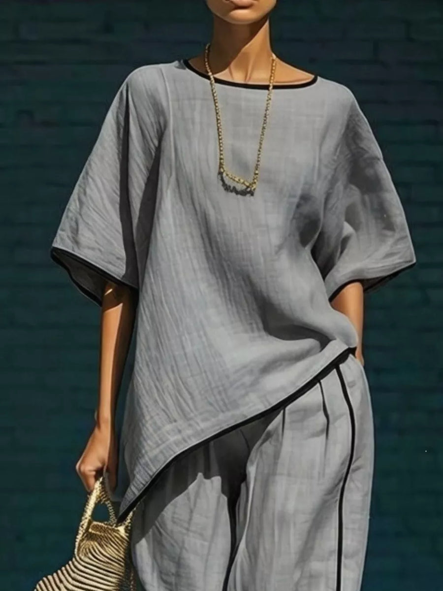 Gray two-piece set with contrast trim, featuring a relaxed top and cropped pants.