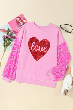Pink sweatshirt with sequin sleeves and a red glitter heart graphic that says love.