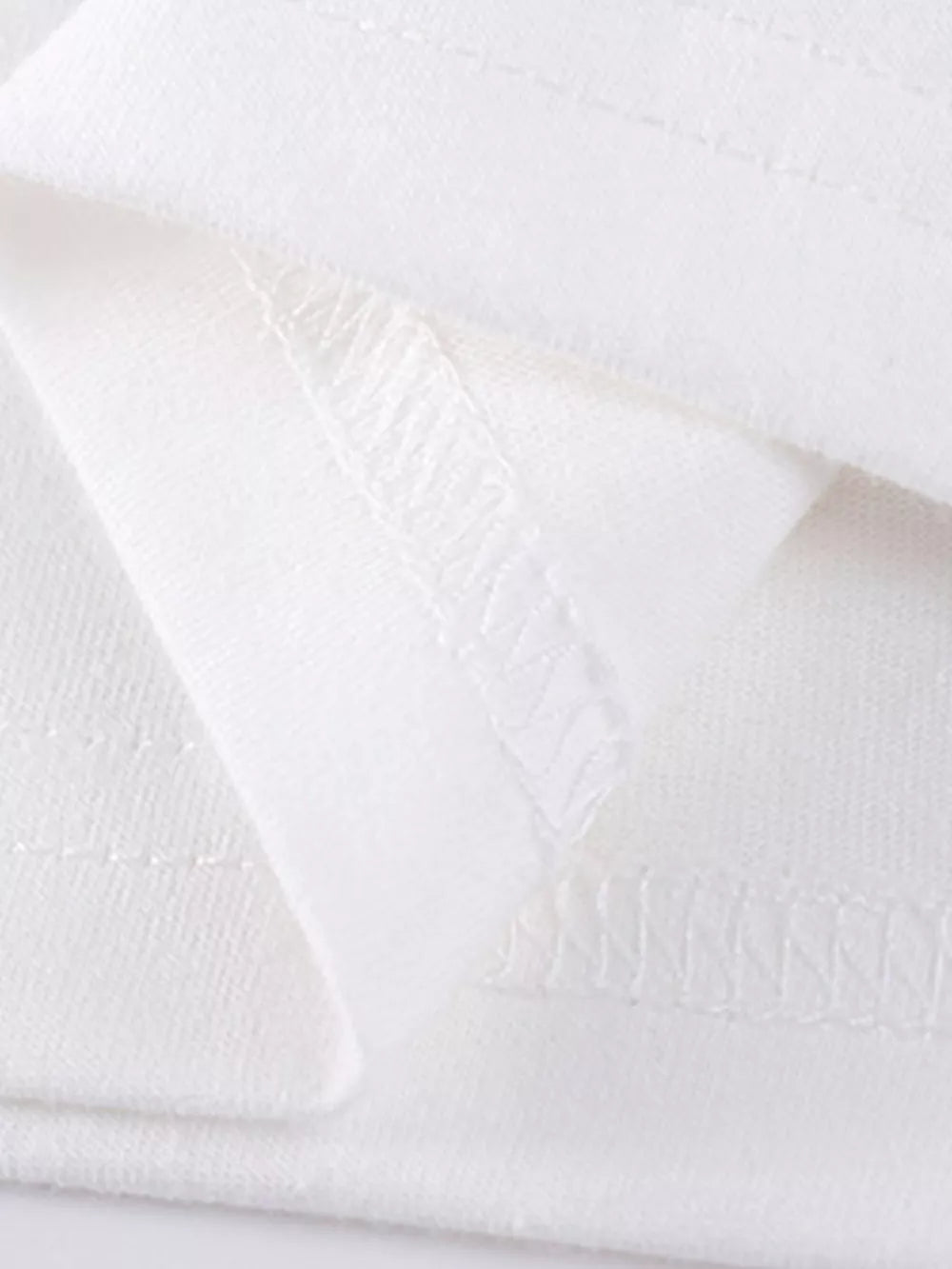 White cotton girls' undershirt detail showing stitching and fabric texture.