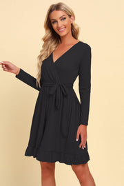 Black wrap dress with long sleeves, tie waist, and ruffled hem.