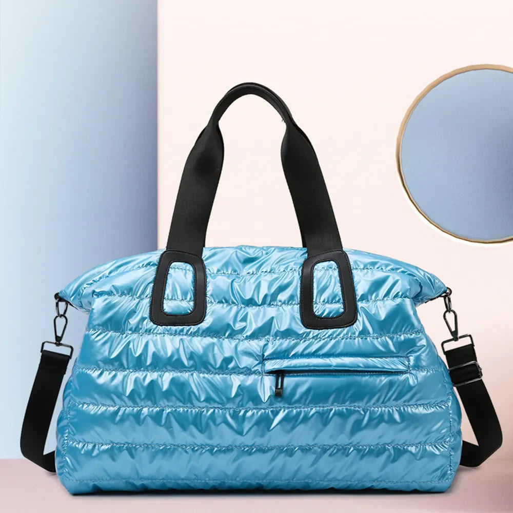 Glossy padded holdall bag in cerulean with black straps and a front zip pocket.