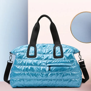 Glossy padded holdall bag in cerulean with black straps and a front zip pocket.