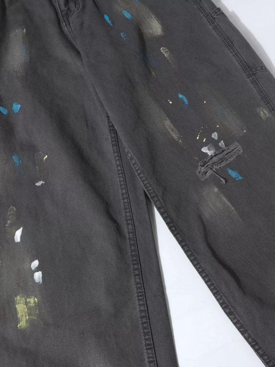 Distressed charcoal wide-leg sweatpants with paint splatter detail and visible stitching.