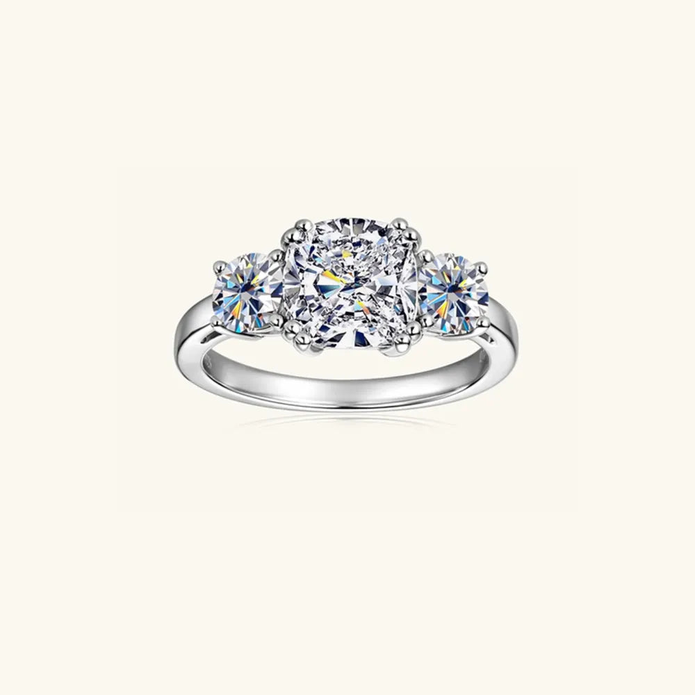 Silver three-stone cushion cut moissanite ring with a central square stone and two round side stones.