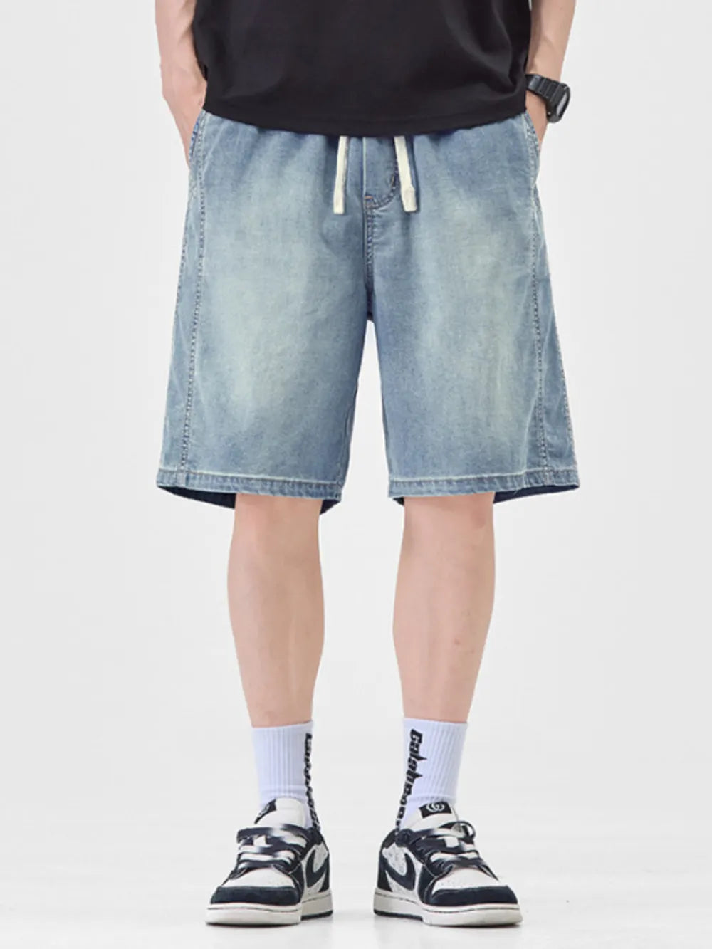 Men's light blue loose fit denim shorts with drawstring waist and distressed wash.