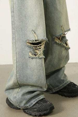 Light wash distressed denim palazzo trousers with wide legs and ripped details.