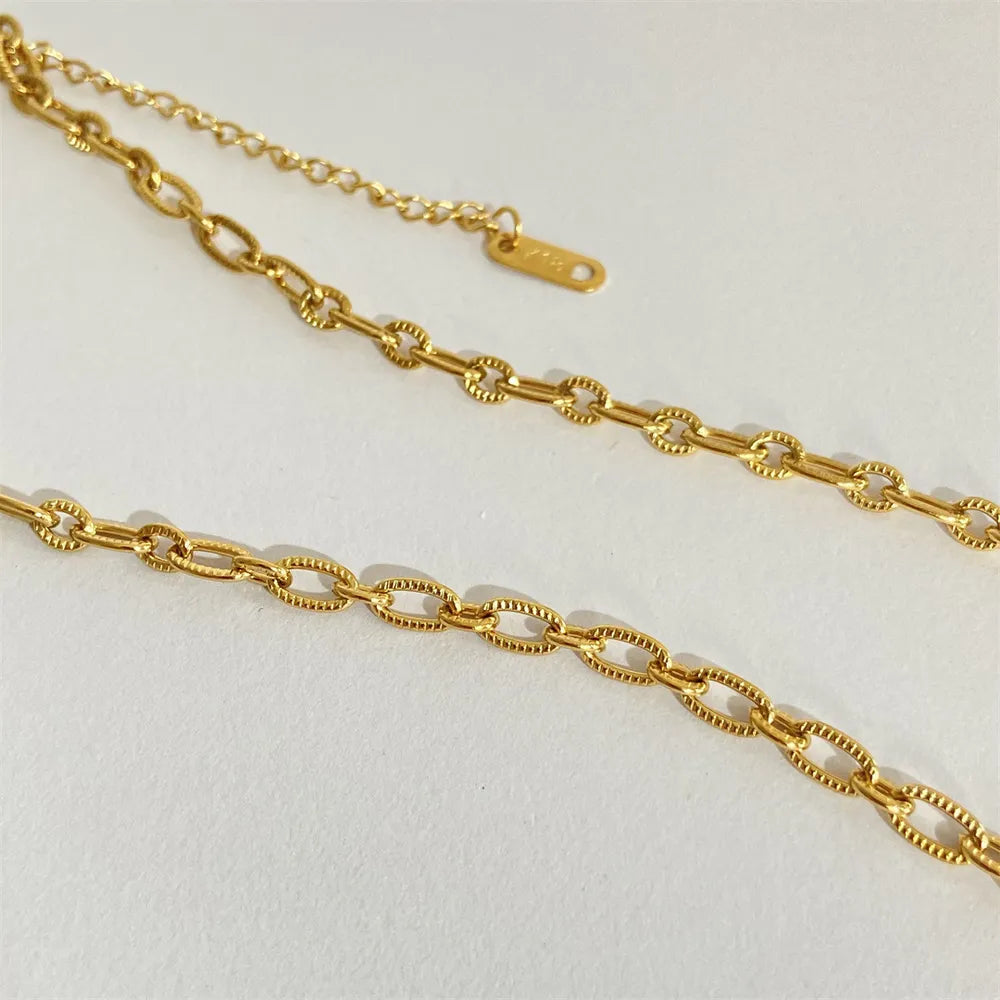 Gold sunburst medallion chain necklace with textured oval links and adjustable clasp