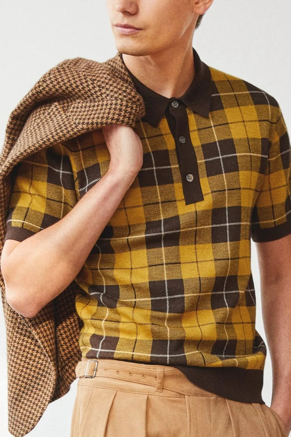 Checked knit polo with contrast trim in plaid, featuring a buttoned neckline and short sleeves.