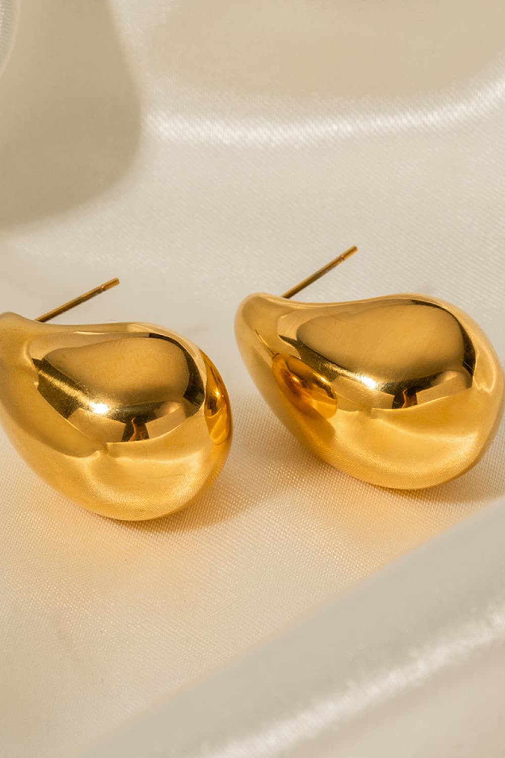 Sculptural gold teardrop stud earrings with a polished finish.