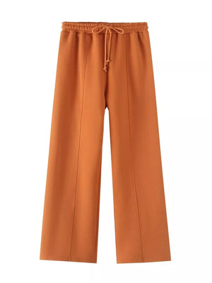 Orange casual wide-leg pants with drawstring waist and seam detail.