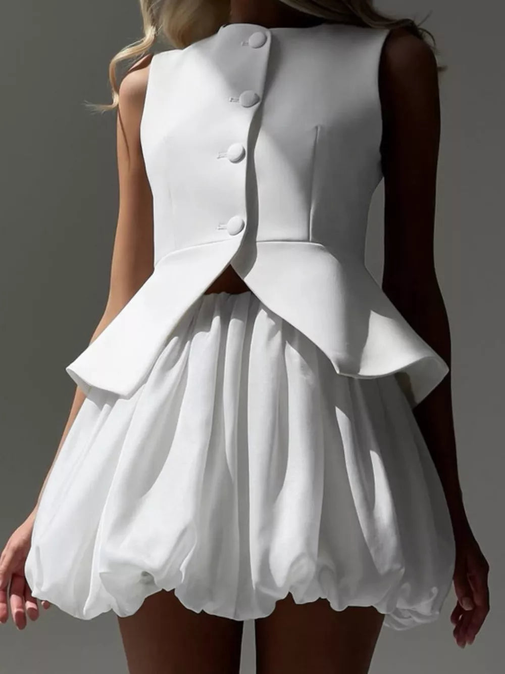 White sleeveless peplum vest with button front and bubble hem skirt