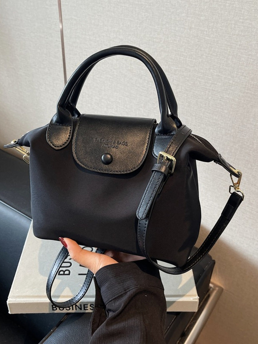 Black nylon crossbody bag with leather flap and top handles.