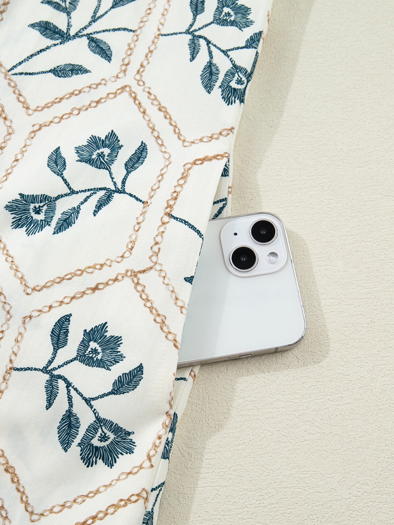 Floral print mini dress with polo collar and button detail, showing a side pocket holding a phone.