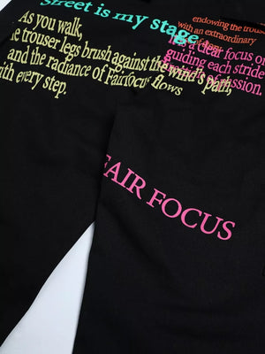 Black cargo pants with colorful text print and pink "FAIR FOCUS" graphic detail.