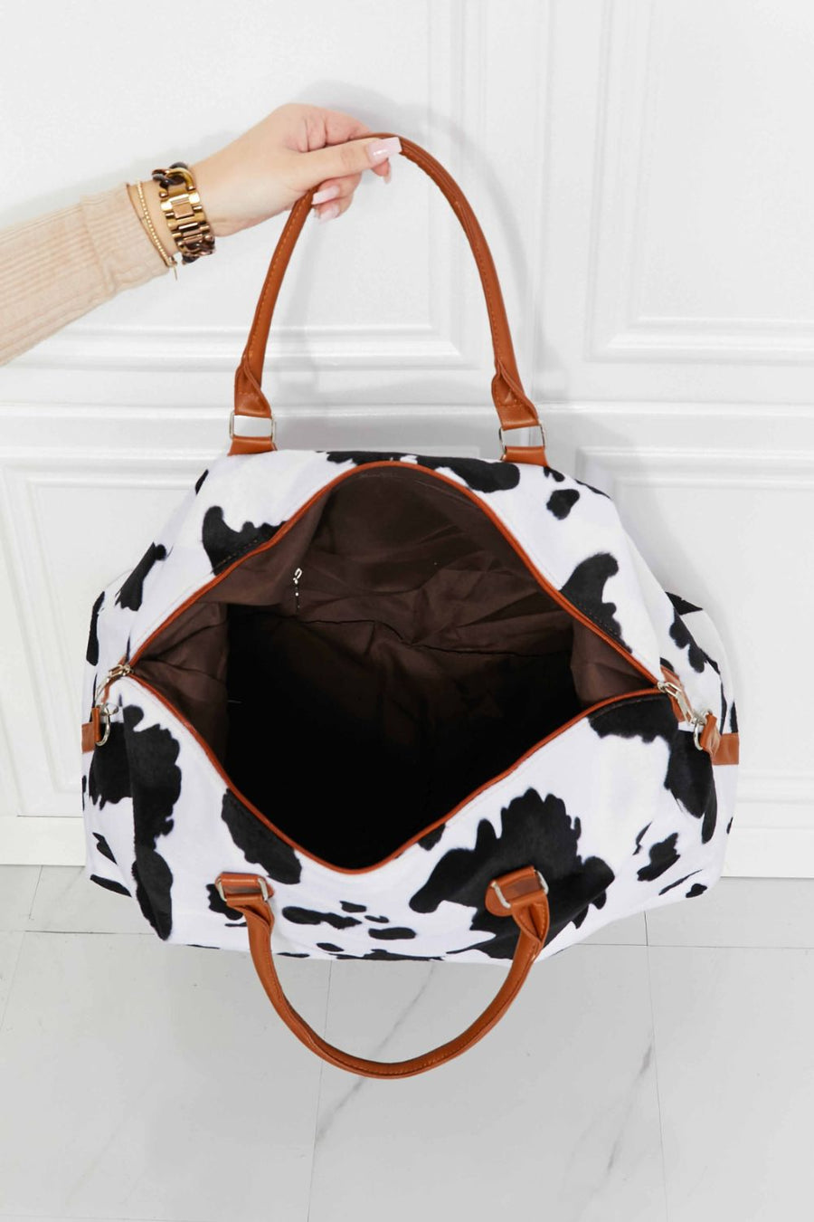 Cowhide print duffel bag with brown leather handles and trim