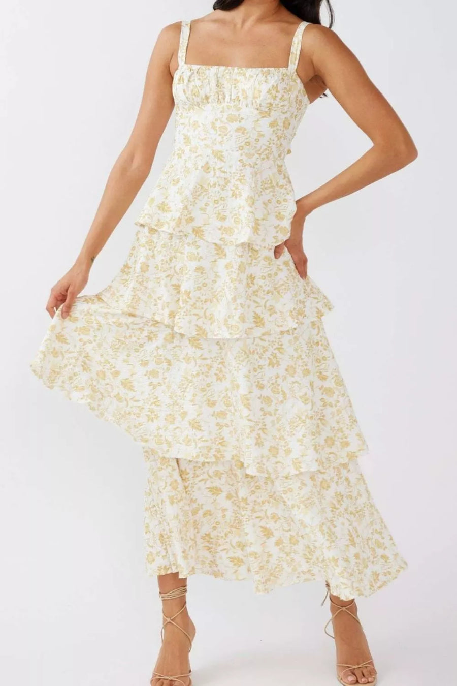 Tiered maxi dress with square neck, spaghetti straps, and yellow floral print on white fabric.