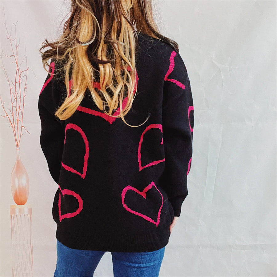 Black acrylic sweater with pink heart outline pattern, crew neck, long sleeves.