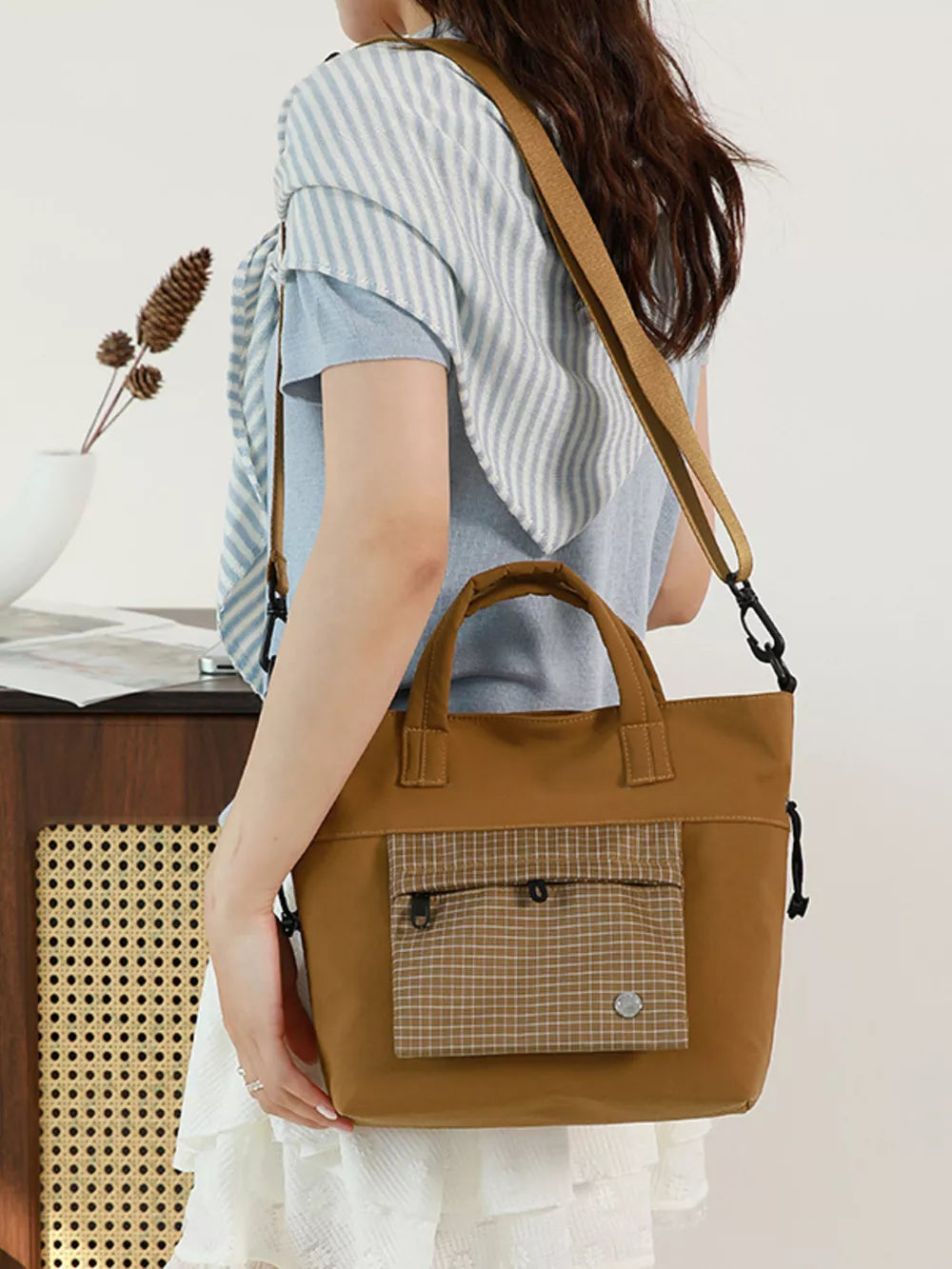 Brown nylon crossbody bag with plaid pocket detail and top handles.