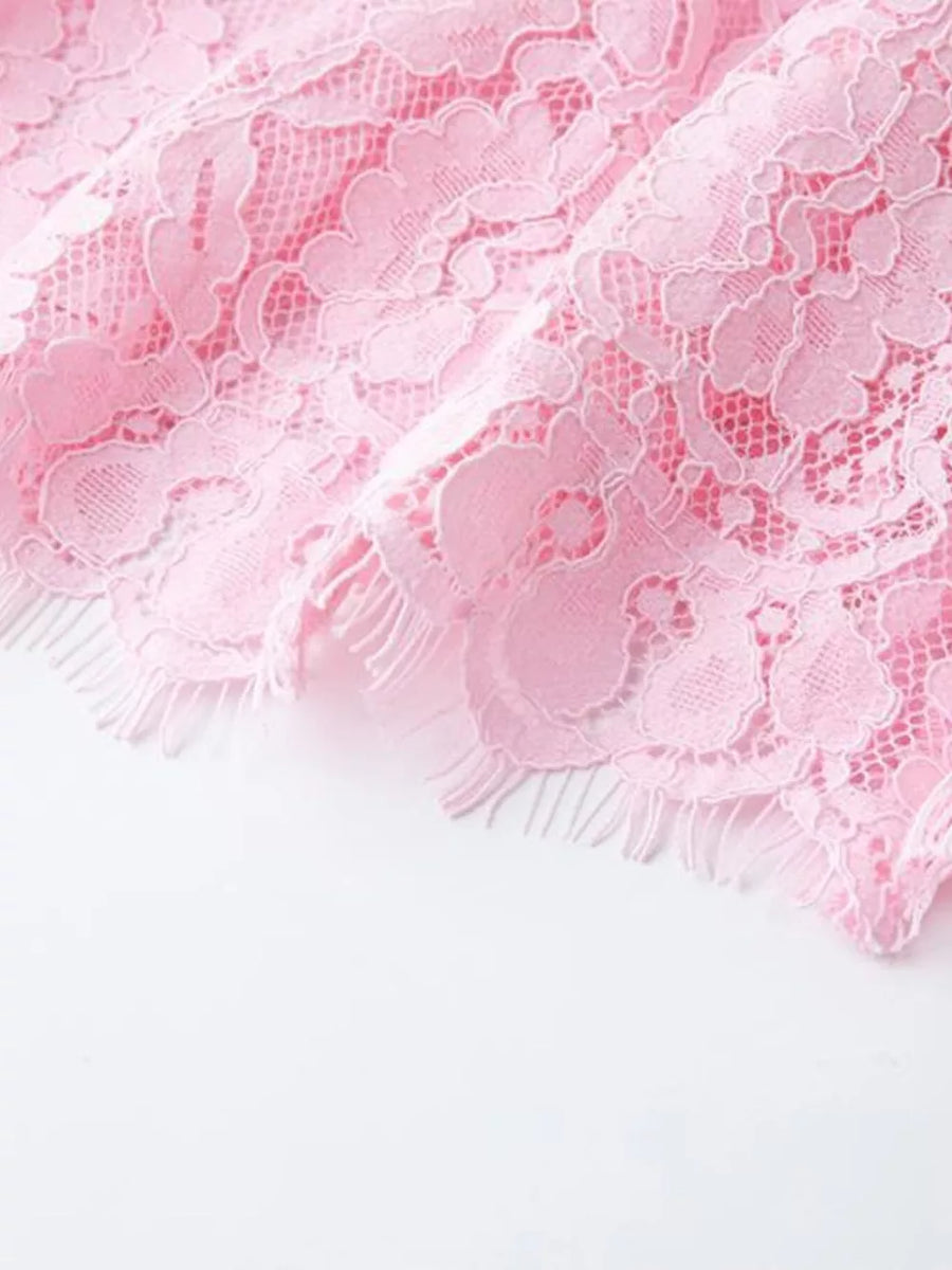 Pink lace midi dress detail with scalloped hem and fringe.