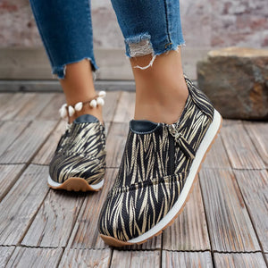 Zebra print slip-on flats with side zipper detail and white soles.