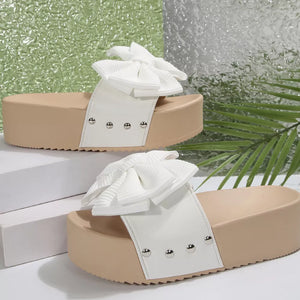 White ribbed bow accent platform sandals with studded white straps and tan soles.