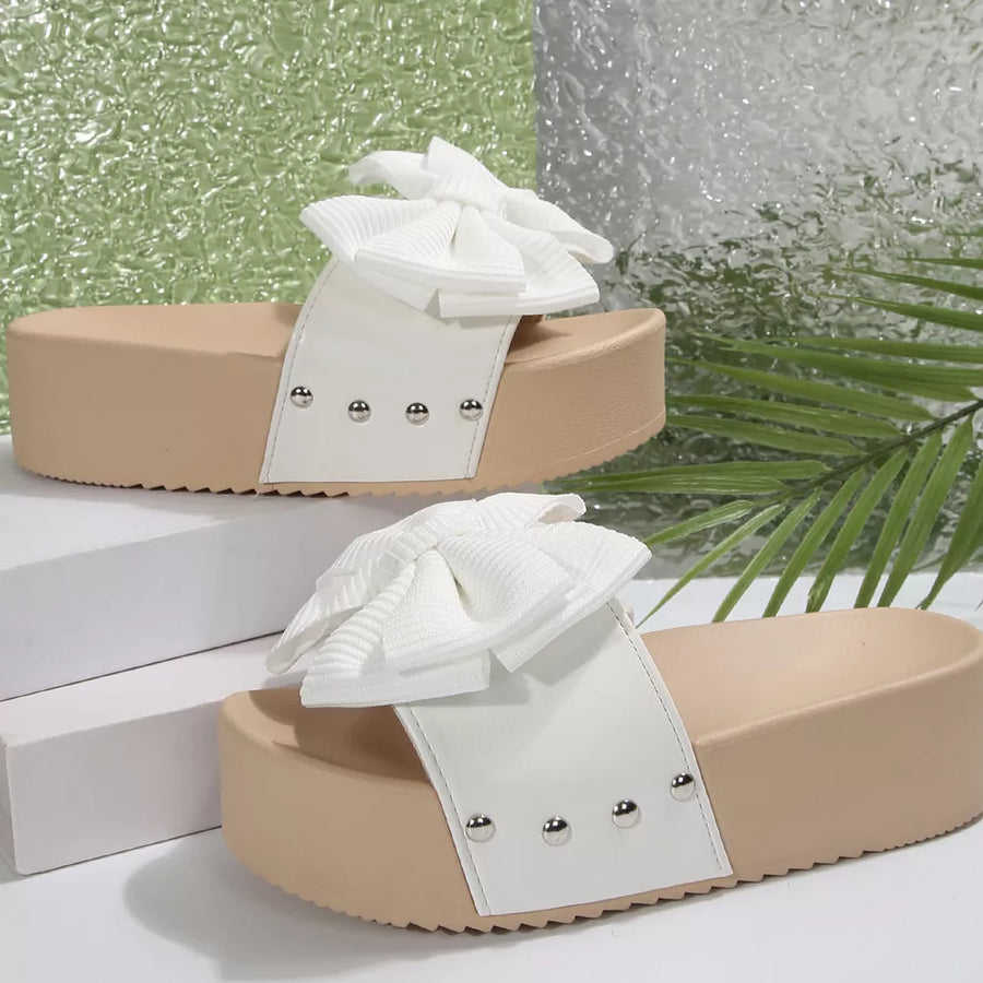 White ribbed bow accent platform sandals with studded white straps and tan soles.