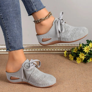 Gray perforated lace-up mule flats with open back and decorative stitching.