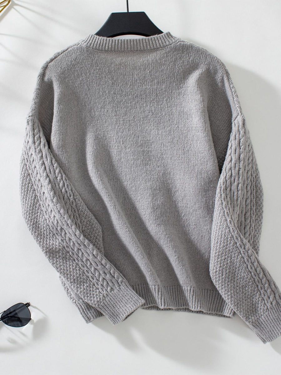 Gray cable knit cardigan with textured sleeves and ribbed cuffs.