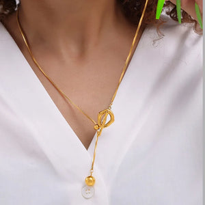 Gold lariat necklace with toggle closure and bead detail.