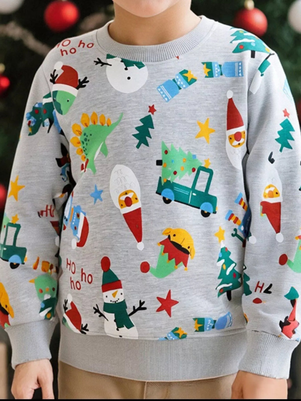 Gray crewneck sweatshirt with festive Christmas print featuring snowmen, Santa, dinosaurs, and trees.