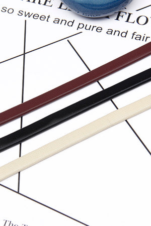 Geometric buckle waist belt in black, cream, and wine with ribbed texture.