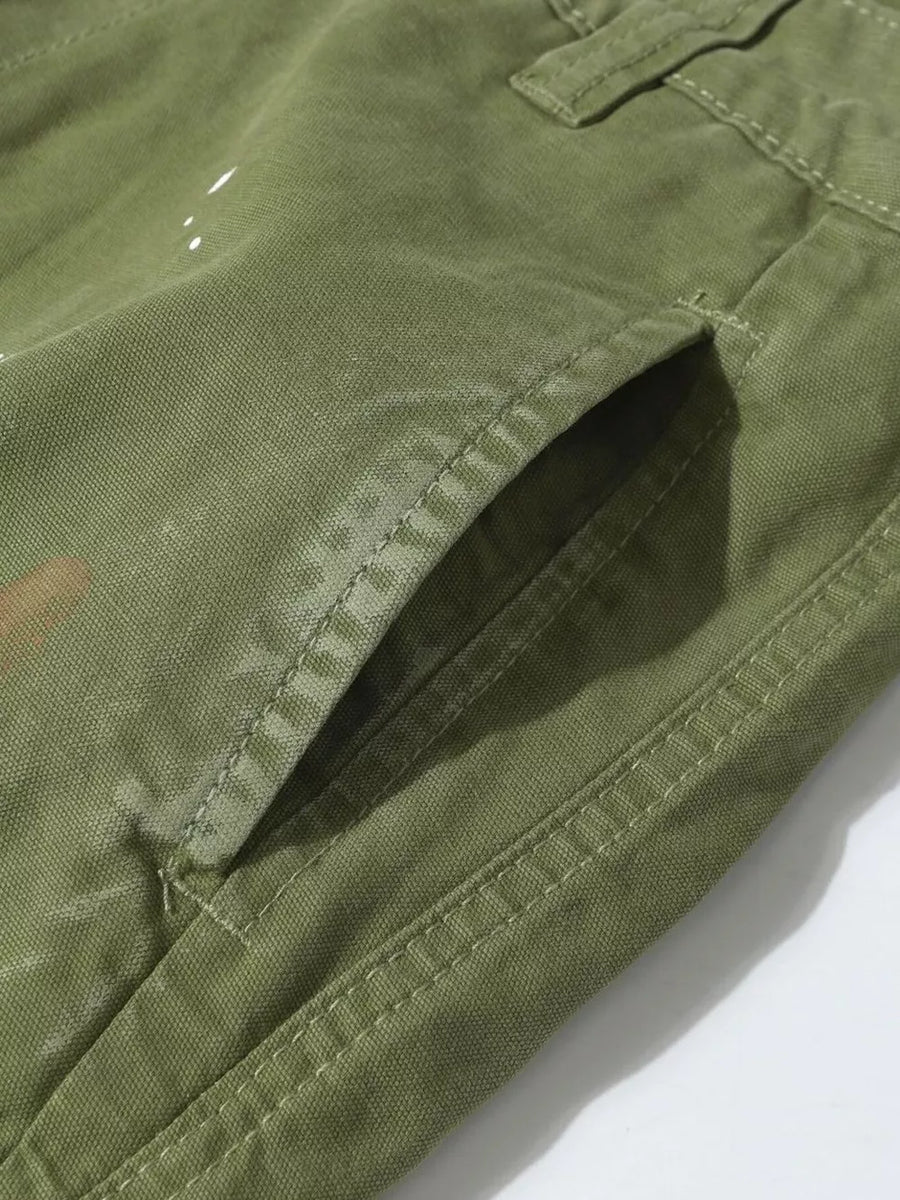 Green distressed cargo pants with white paint accents and visible stitching detail.