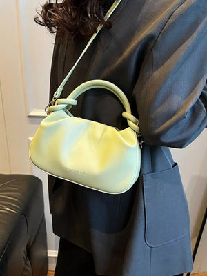 Mini ruched crossbody bag in light green with knotted handle detail and embossed text.