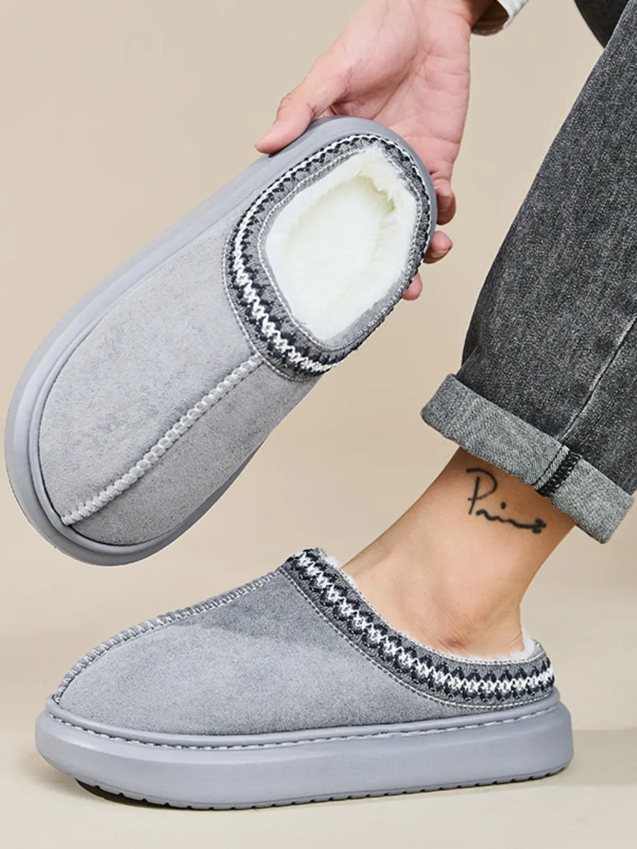 Gray shearling house slippers with embroidered trim and plush lining.
